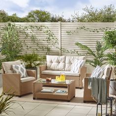 an outdoor living area with wicker furniture and potted plants on the side walk