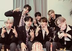 a group of young men sitting next to each other in front of a birthday cake