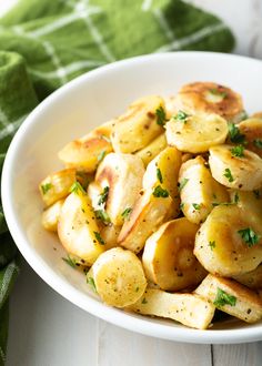 a white bowl filled with potatoes and garnished with parsley on the side