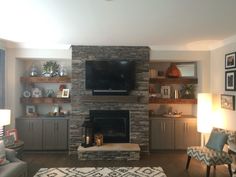 a living room with a large stone fireplace and built - in entertainment center on the wall