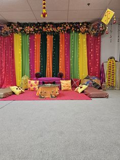 a colorful stage set up for a party with lots of pillows and decorations on the floor