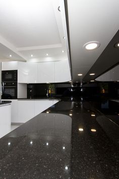 a kitchen with black counter tops and white cupboards on the walls, along with an island