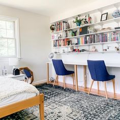 a bed room with a neatly made bed and two chairs next to a book shelf