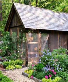 a garden shed with flowers and plants around it