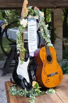 two guitars sitting on top of a wooden table next to a sign that says,