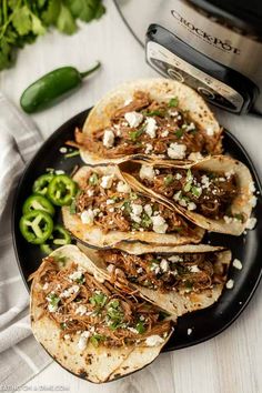 three shredded pork tacos on a plate next to an instant pot