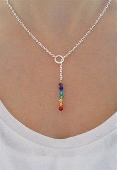 a woman wearing a silver chain necklace with multi colored beads