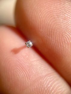 a close up of a person's finger with a diamond ring on it