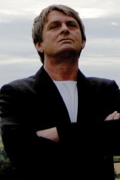 a man standing with his arms crossed and looking off into the distance