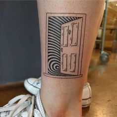 a black and white photo of a person's leg with a door tattoo on it