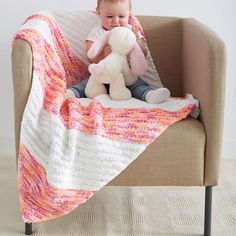 a baby sitting on a couch holding a stuffed animal