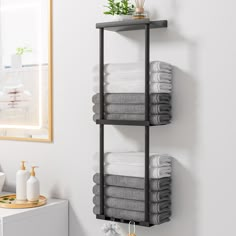 the towel rack is made from metal and holds several folded white towels, one in grey