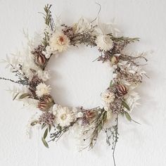 a white wreath with dried flowers and greenery