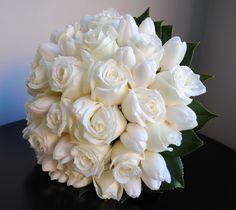 a bouquet of white roses sitting on top of a table