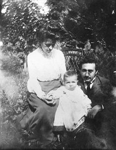 an old black and white photo of two people with a baby sitting on a bench