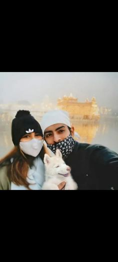 a man and woman pose for a photo with a dog wearing a mask on their face