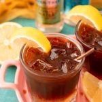 two glasses filled with liquid sitting on top of a table next to sliced lemons