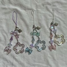 four pairs of earrings with charms attached to them on a white cloth covered tablecloth