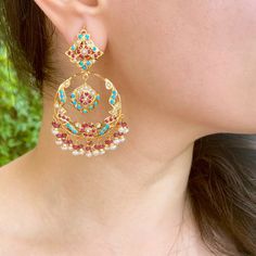 This gold plated silver chandbali earrings feature firoza, pearls and synthetic red stones to create a timeless aesthetic. The earrings are decorated with high-grade pearls, turquoises and rubies to craft an intricate, special design. The earrings come with a bombay screw closure. All of Rudradhan's Gold Plated Jewellery is made using 925 Silver, real freshwater pearls and high quality ruby, emerald and sapphire beads. The default choice for studded stones used is synthetic that closely resemble Elegant Turquoise Kundan Earrings, Turquoise Chandbali Jewelry With Latkans, Elegant Turquoise Earrings For Festivals, Elegant Turquoise Earrings For Festive Occasions, Elegant Turquoise Earrings For Festive Season, Red Chandbali Gold Plated Jewelry, Elegant Turquoise Meenakari Earrings, Red Fusion Earrings With Intricate Design, Festive Turquoise Temple Jewelry Earrings