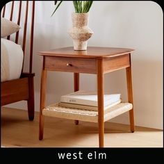 a small wooden table with a flower pot on it and some books in front of it