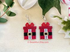 a pair of red and black beaded earrings sitting on top of a table