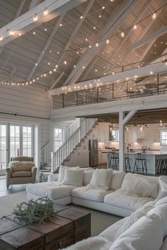 a living room filled with white furniture and lots of lights hanging from the ceiling above