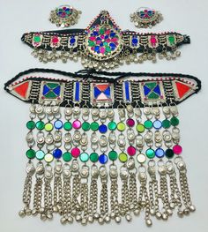 * This is a complete Afghan Kuchi set including a choker, Matha Patti, and hoops. Each piece exhibits multicolor glass stone inlay, use of solid metal alloy, beads, bells, and motifs. The metallic weaving technique is used in the making of the choker and mathapatti while the earrings are made in chandballi style. * The traditional Afghan Kuchi jewelry is known for its variety and use of several materials such as colorful glass jewels, coins, bells, dangles, beadwork, embroidery, mirrors, laces, Bohemian Jewelry With Motifs For Celebration, Traditional Multicolor Jewelry For Traditional Ceremonies, Traditional Multicolor Jewelry For Ceremonies, Multicolor Bohemian Jewelry For Traditional Ceremonies, Bohemian Jewelry With Mirror Work For Navratri, Bohemian Mirror Work Jewelry For Festivals, Traditional Festival Jewelry With Motifs, Bohemian Jewelry With Mirror Work For Festivals, Bohemian Jewelry For Ceremonial Festival