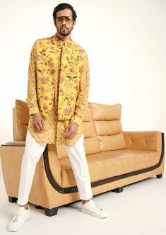 The mustard Caribbean bandi is constructed with a lightweight malai cotton fabric. The age-old floral jaal print dates back several decades and while it remains a classic, its color palette keeps it fresh. This bandi is a sleeveless jacket featuring a mandarin collar, one chest pocket and two hip pockets on each side. It is finished with ornate golden buttons and the bandi is fully lined. Please note: buttons are subject to availably, if unavailable we will replace the buttons pictured here with a suitable alternative. Cotton Nehru Jacket For Festivals, Cotton Nehru Jacket Straight Kurta For Festivals, Summer Yellow Bandhani Print Kurta, Yellow Bandhani Print Kurta For Summer, Yellow Cotton Kurta With Bandhani Print, Cotton Bollywood Nehru Jacket For Festive Occasions, Bollywood Style Cotton Nehru Jacket For Spring, Designer Cotton Bandhgala With Printed Motifs, Cotton Bandhgala With Printed Motifs