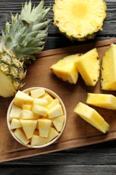 sliced pineapples and other fruits on a cutting board next to a small bowl