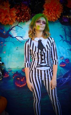 a woman with green hair and makeup is dressed up as beetlegy girl in front of a backdrop