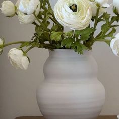 a white vase filled with flowers on top of a table