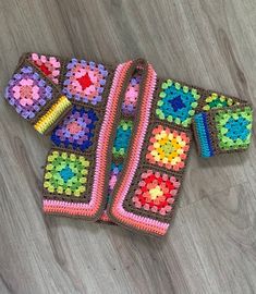 two crocheted sweaters sitting on top of a wooden floor