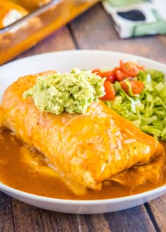 an enchilada with guacamole and lettuce on top