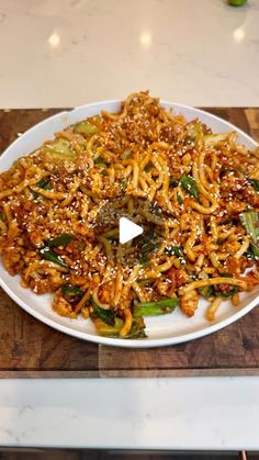 a white plate topped with noodles and veggies on top of a wooden cutting board