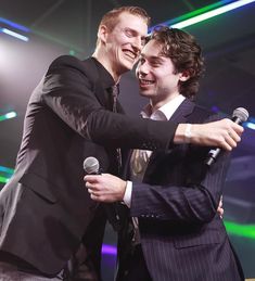 two men hugging each other while holding microphones