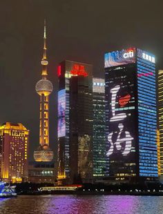 the city skyline is lit up at night with bright lights and buildings in the foreground