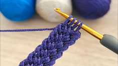 a crochet hook with yarn in the background and balls of thread to the side