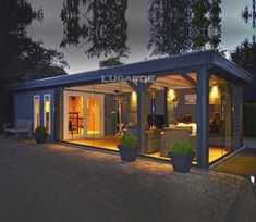 a small house is lit up at night with lights on the porch and patio area