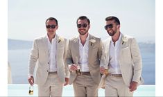 three men in suits and sunglasses standing next to each other holding champagne glasses, smiling at the camera