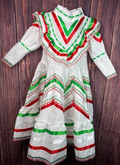 Gorgeous traditional Jalisco style dress. Also used for folklore dancing. Dress base is white embellished with red and green lace and ribbons. Zipper closure on back and belt ties to adjust fit. Dresses Run Big Size 1 - skirt is approx 9 1/2 in long (neck to waist) 18 in long (waist to floor) Size 2 -skirt is approx 9 3/4 in long (neck to waist) 20 in long (waist to floor) Toddler Mexican Dress, Jalisco Dress, Dancing Dress, Boutique Owner, Mexican Dresses, Long Neck, Dance Dress, Green Lace, Belt Tying