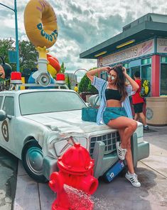 a woman sitting on top of a car next to a fire hydrant