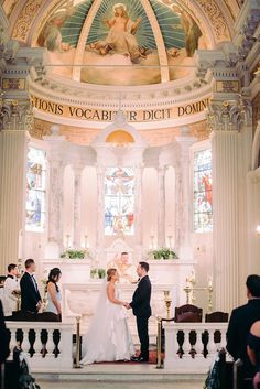 a bride and groom standing in front of the alter during their wedding ceremony at st john's cathedral