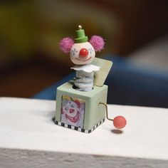 a small toy clown sitting on top of a box