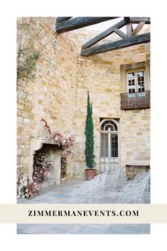 two white chairs sitting in front of a stone building