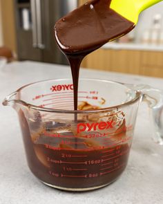 chocolate sauce being poured into a measuring cup