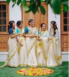 a group of women standing next to each other in front of a building with flowers on the ground