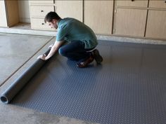 a man kneeling down on the floor with a large roll of black material in front of him