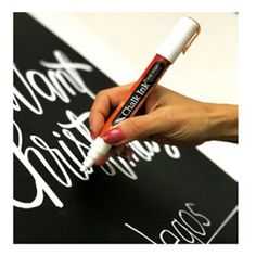 a person is writing on a blackboard with white lettering and a pen in their hand