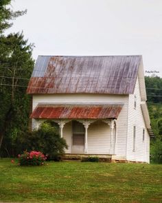 an old white house sitting in the middle of a field