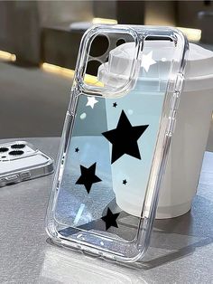 a clear case with black stars on it sitting next to a white cup and cell phone